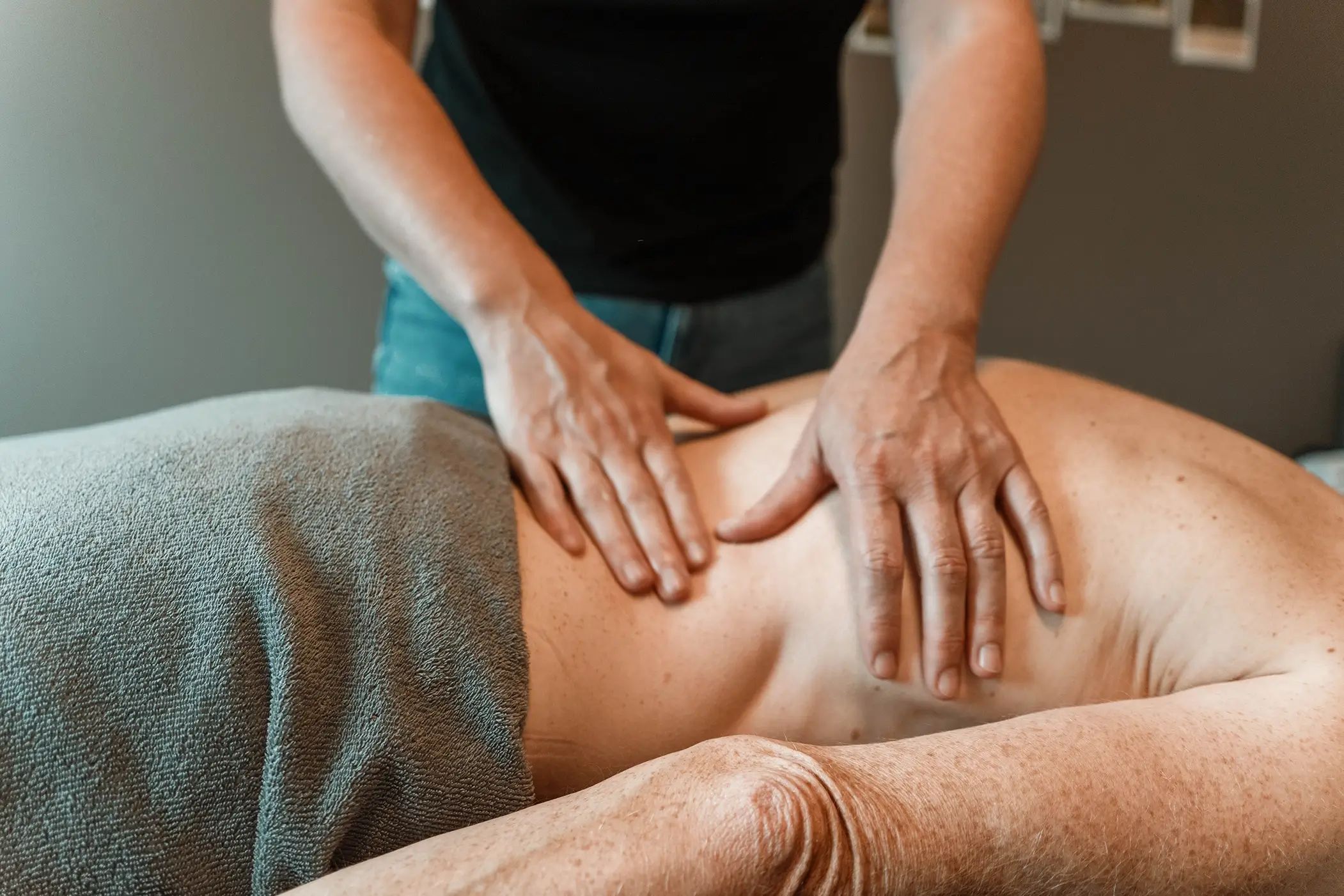 Close up van de handen van Lesly die een been aan het masseren is