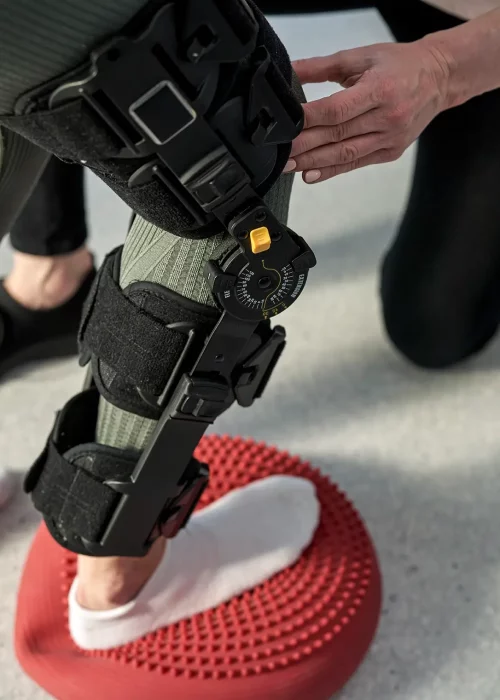 Close up van been met een brace omheen die oefeningen aan het doen is